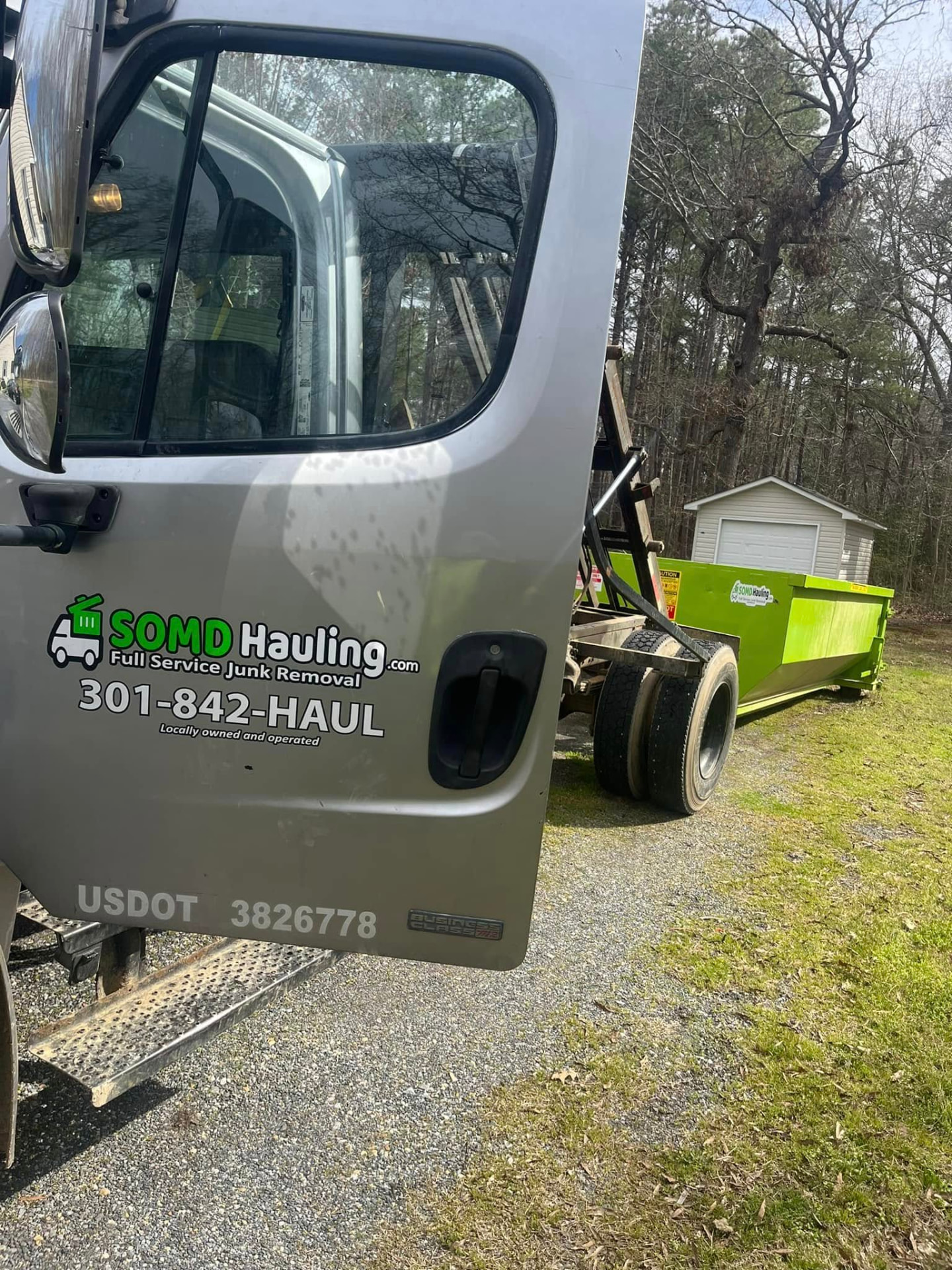 Roll-off truck delivering a green dumpster